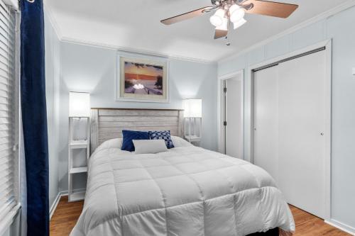 ein weißes Schlafzimmer mit einem Bett und einem Deckenventilator in der Unterkunft Starfish Hall in Atlantic Beach
