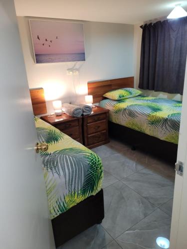 a room with two beds and a desk with two lamps at Paradise Holiday Apartments in Cairns