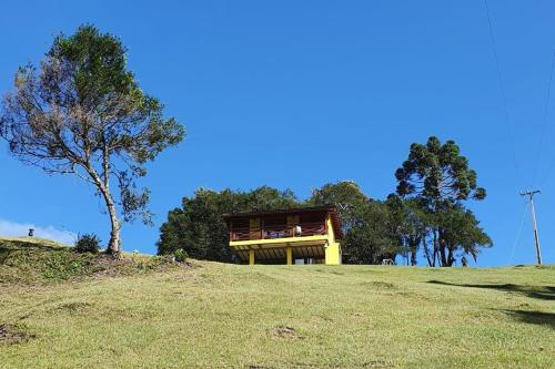 a house on top of a hill with a tree at Rancho 4 Corações in Urubici