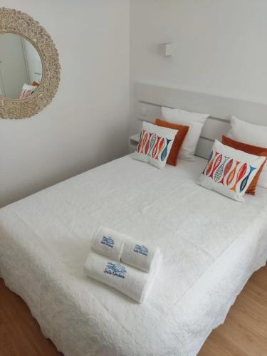 a white bed with towels on it with a mirror at Cabana Sete Ondas in Nazaré