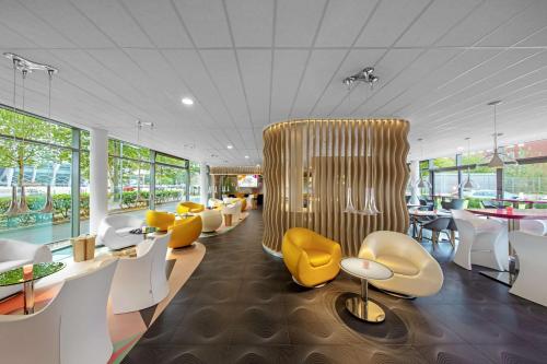 um restaurante com mesas e cadeiras amarelas e brancas em prizeotel Bremen-City em Bremen