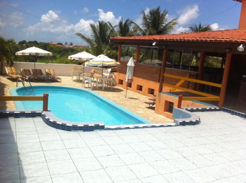 a large swimming pool next to a building with a house at Pousada Zekas in Jacumã