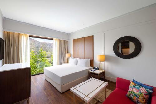 1 dormitorio con cama blanca y sofá rojo en Radisson Blu Resort Kumbhalgarh, en Kumbhalgarh