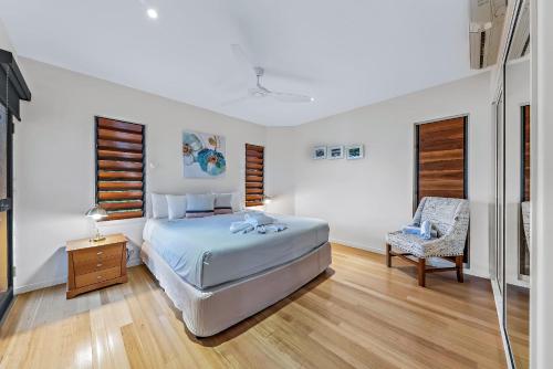 a bedroom with a bed and a chair at Shutehaven Villa in Shute Harbour