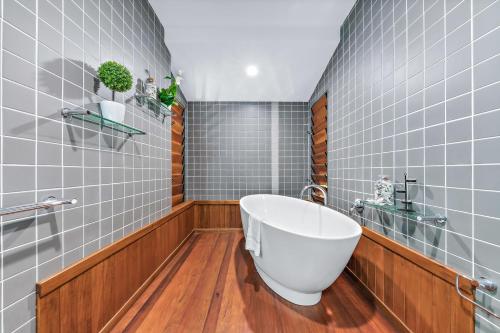 a bathroom with a white tub and wood floors at Shutehaven Villa in Shute Harbour