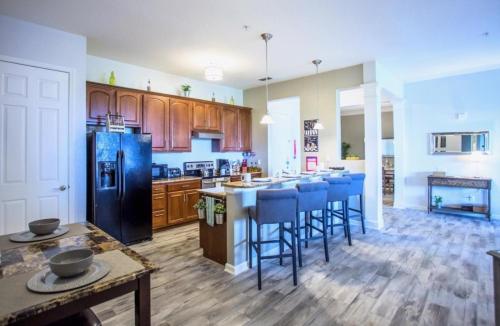 una cocina con armarios de madera y taburetes de barra azul en LakeView Penthouse 3 Bedroom In Vista Cay condo en Orlando