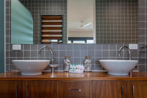 two sinks on a wooden counter in a bathroom at Shutehaven Villa in Shute Harbour