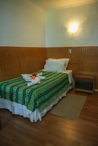 a bedroom with a bed with a green blanket at Cabañas MANA NUI INN in Hanga Roa
