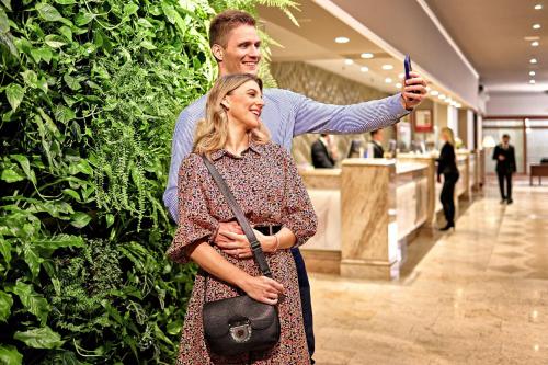 a man taking a picture of a woman in front of a plant at The Westin Zagreb in Zagreb