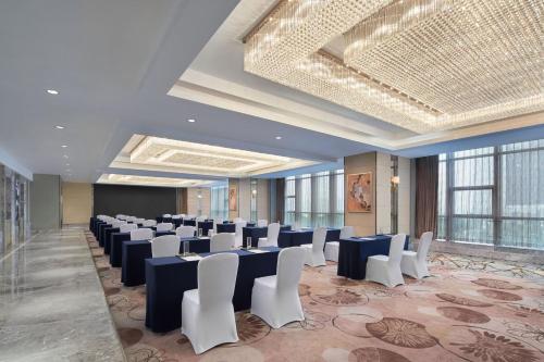 una stanza con file di tavoli e sedie bianche di Sheraton Nanchang Hotel a Nanchang
