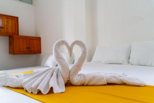 two towel swans sitting on top of a bed at Patty House Galapagos in Puerto Ayora