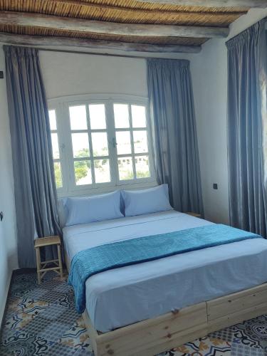 a bedroom with a large bed with a window at Dar Aya Dmina in Demina