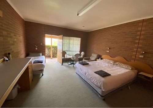 a bedroom with a large bed and a living room at Railway Hotel Motel Peterborough in Peterborough