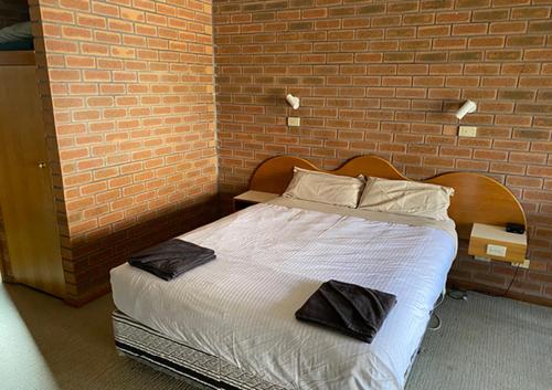 Cama en habitación con pared de ladrillo en Railway Hotel Motel Peterborough, en Peterborough