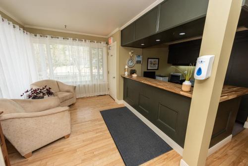 a living room with a kitchen with a counter and a couch at Auberge Beausejour in Les Éboulements