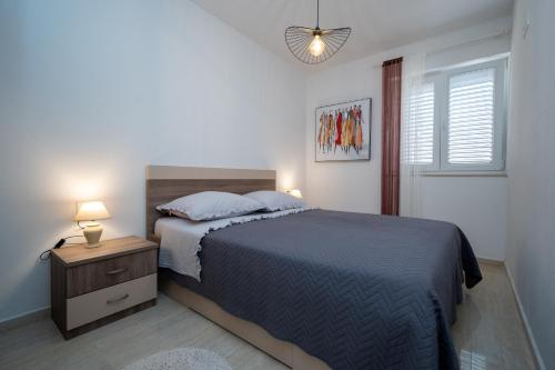 1 dormitorio con 1 cama y mesita de noche con lámpara en Apartments by the sea Sali, Dugi otok - 19880, en Sali