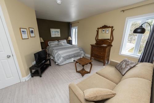 a living room with a bed and a couch at Auberge Beausejour in Les Éboulements