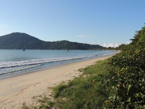 a beach with the ocean and mountains in the background at Pousada Don Diego in Ubatuba