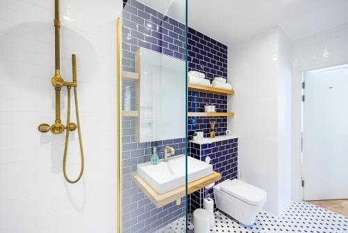 a blue tiled bathroom with a sink and a toilet at Apartment Near Canary Wharf 02 Arena & Excel in London