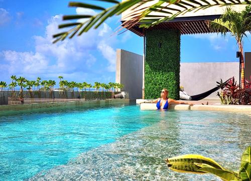 a woman sitting in a swimming pool at a resort at Sofía Boutique Condos by Bunik in Playa del Carmen