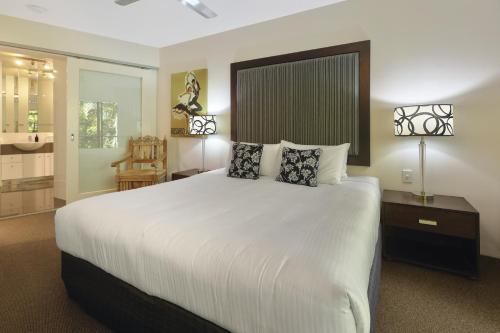 una camera da letto con un grande letto bianco con due cuscini di The Cove Noosa - Apartment 20 a Noosa Heads