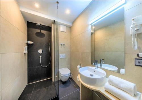 uma casa de banho com um lavatório, um chuveiro e um WC. em Hotel Business Bay das ehemalige Staycation Hotel em Sindelfingen