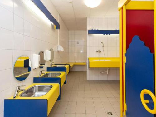 a public bathroom with yellow and blue counters and sinks at Bungalow in Waxweiler in the Southern Eifel in Waxweiler