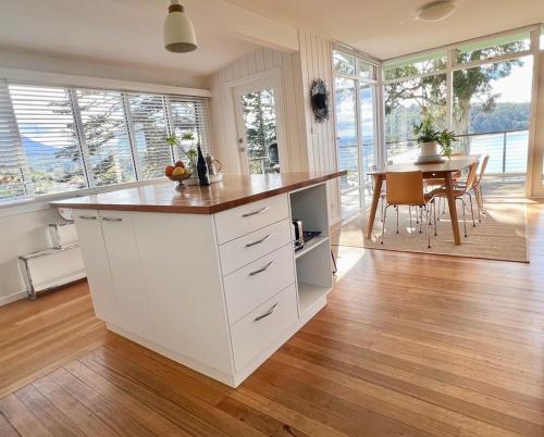 a kitchen with a large white island with a table at Beach House, Stunning Views of Kingston Beach in Kingston Beach