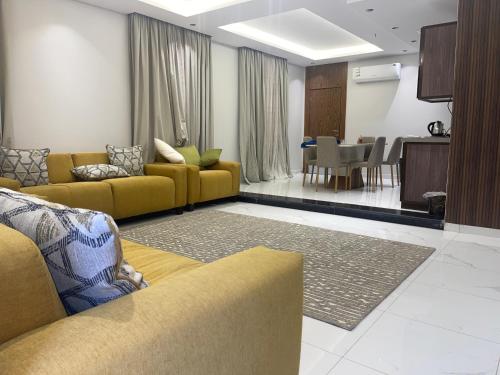 uma sala de estar com sofás amarelos e uma sala de jantar em فلل بيات الفيصل Bayat Al Faisal Villas em Baljurashi
