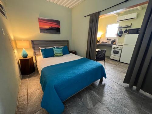 a bedroom with a bed with blue sheets and a kitchen at The Vieques Guesthouse in Vieques