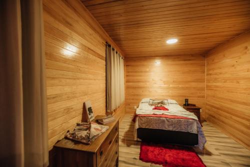 1 dormitorio con 1 cama en una habitación de madera en Pousada Vila Felicita, en São Valentim