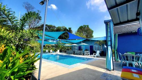 een zwembad met blauwe parasols en stoelen naast een huis bij Hidden Palms Inn in san juan la union