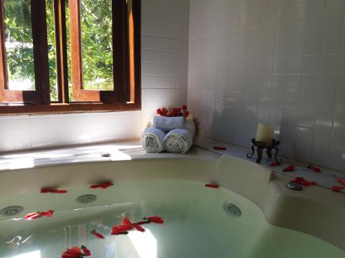 a bathroom with a bath tub with red flowers in it at Pousada Vila Mato Verde in Morro de São Paulo