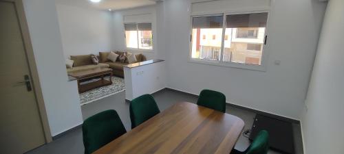 una camera con tavolo in legno e sedie verdi di Logement familial a Selouane