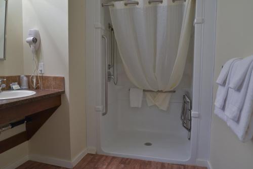 a white bathroom with a shower and a sink at Days Inn by Wyndham Lamont in Lamont