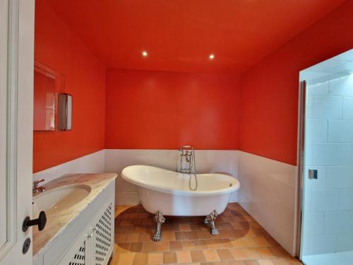 LandeleauにあるEstate in Landeleau near Aulne Riverの白い浴槽とオレンジ色の壁のあるバスルーム