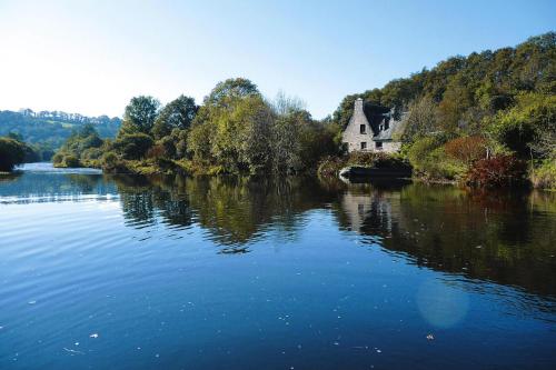 a house sitting on the side of a river at Mill in Brittany by River Aulne with Kayaks in Landeleau