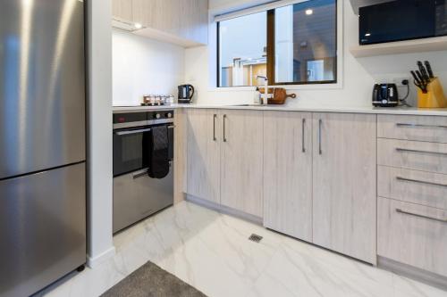 a kitchen with wooden cabinets and a stainless steel refrigerator at Charming Downtown hideaway 1 bed 1 bath in Christchurch