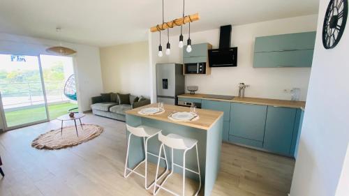 a kitchen and living room with blue cabinets and a table at Appartement Océan View in Le Robert