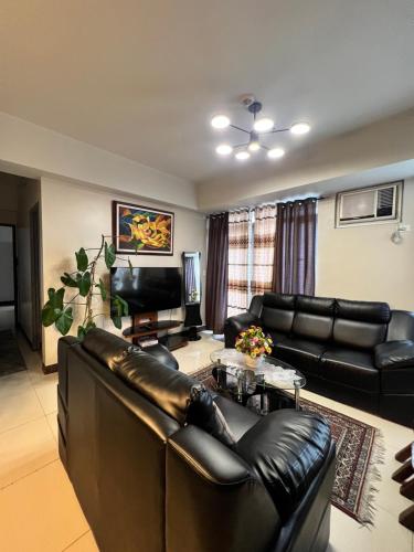 ein Wohnzimmer mit einem Ledersofa und einem TV in der Unterkunft Manhattan Heights Tower A in Manila