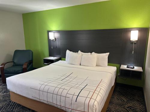 a hotel room with a large bed and a chair at La Quinta Inn by Wyndham Omaha Southwest in Omaha