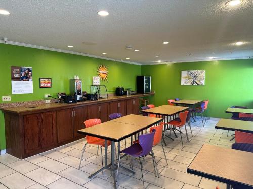 un restaurante con mesas, sillas y paredes verdes en La Quinta Inn by Wyndham Omaha Southwest, en Omaha
