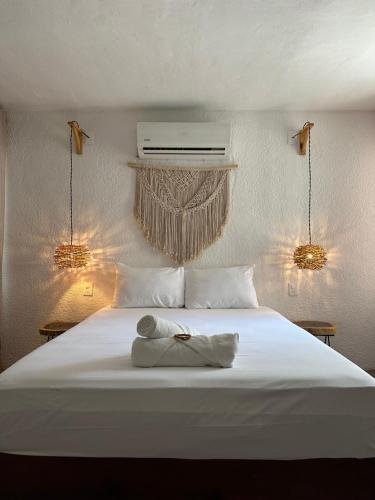 Una cama blanca con dos toallas encima. en Hotel and hostel KAB en Cancún