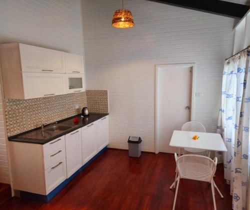 uma cozinha com armários brancos e uma mesa e cadeiras em The Crow's Nest Resort Fiji em Korotogo