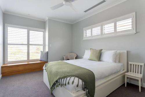 a white bedroom with a bed and two windows at Oceanic I Private Properties in Dawesville