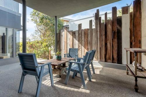 a patio with chairs and a wooden table and a fence at Oceanic I Private Properties in Dawesville