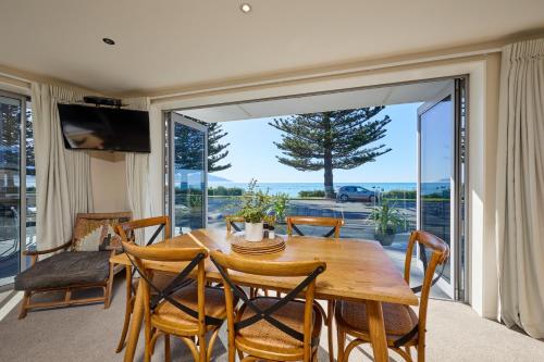 a dining room with a table and chairs and a large window at Kaikoura Waterfront Apartments in Kaikoura