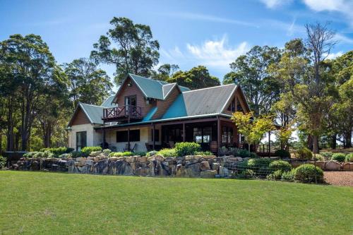a house with a stone wall in front of a yard at Tintagel Estate I Private Properties in Forest Grove