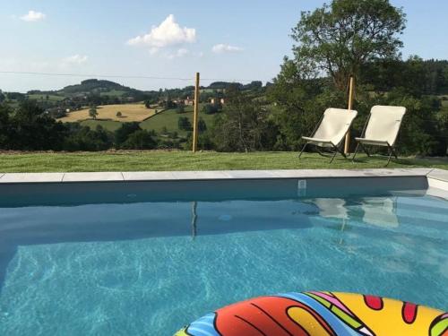 two chairs sitting next to a swimming pool at Gîte avec piscine, cheminée, jardin, et animaux acceptés - FR-1-496-32 in Belmont-de-la-Loire