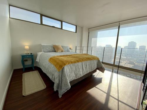 a bedroom with a bed and a large window at Loft Panoramico - Santiago in Santiago